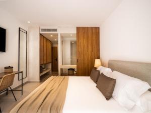 Schlafzimmer mit einem großen weißen Bett und einem Schreibtisch in der Unterkunft Hotel Porfirio Picota - Adults Recommended in Zahara de los Atunes