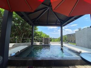 a swimming pool with an umbrella and water at 金漫會館-金瓜石九份景觀民宿-Jien Mount Villas in Jiufen