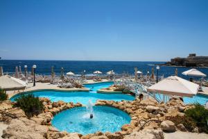 a beach filled with lots of beach chairs and umbrellas at Radisson Blu Resort, Malta St. Julian's in St Julian's