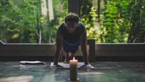 un hombre agachado mirando una vela en The Zen Hostel - Posticum, en Oradea