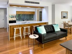 a living room with a black couch and a kitchen at Maggies Beachfront Apartment 9 in Horseshoe Bay
