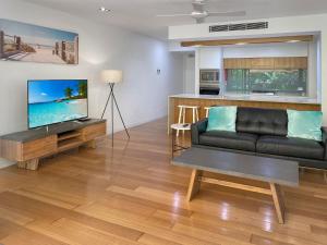 a living room with a black couch and a television at Maggies Beachfront Apartment 9 in Horseshoe Bay