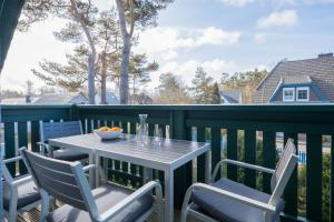 a table and chairs on a balcony with a view of a house at Ferienwohnung Lee Ost 2 3 in Dierhagen