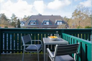 a table and chairs on a deck with a house at Ferienwohnung Lee Ost 2 4 in Dierhagen +2 photos