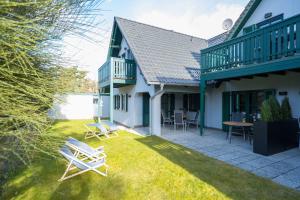 a patio with chairs and a table on a lawn at Ferienwohnung Lee West 2 2 in Dierhagen