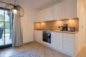 a kitchen with white cabinets and a sink at Ferienwohnung Lee West 2 2 in Dierhagen +3 photos