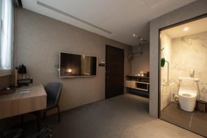 a room with a bathroom with a toilet and a desk at Hotel East Taipei in Taipei