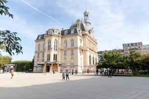 un grand bâtiment avec des personnes qui marchent devant lui dans l'établissement Logement entier:Asnières sur Seine (10mn de Paris), à Asnières-sur-Seine