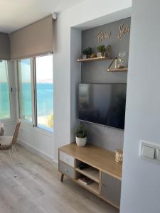 a living room with a flat screen tv and a large window at Bow Sea Apartment in Algarrobo-Costa