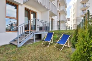 two blue chairs sitting on the grass in front of a building at Apartment Gdańsk Downtown by Renters in Gdańsk
