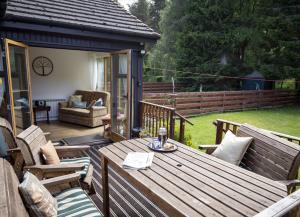 una terraza de madera con mesa y sillas de madera en Croftwood Cottage, en Boat of Garten