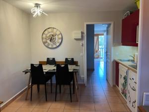 a kitchen with a table and chairs and a clock on the wall at La Résidence Vacances Mondésir appartement 3 étoiles in Monflanquin