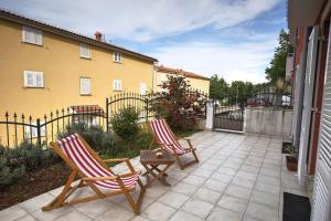zwei Stühle auf einer Terrasse vor einem Haus in der Unterkunft Apartment Sally in Čižići