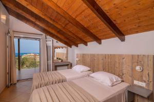 two beds in a bedroom with a balcony at Armonia Boutique Hotel in Meson Yerakarion