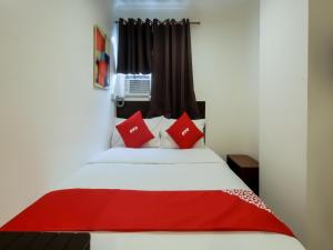 1 dormitorio con cama blanca y almohadas rojas en Super OYO 856 City Stay Inns Slex Makati, en Manila