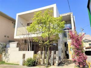 um edifício branco com uma árvore em frente em Kumamoto - House - Vacation STAY 83489 em Kumamoto
