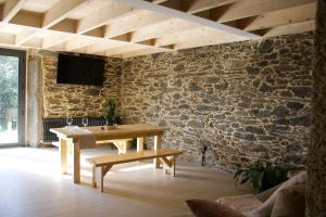 Pokój z drewnianym stołem i kamienną ścianą w obiekcie O lar de San Fins-Casita rural w mieście A Coruña