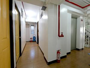 um corredor com paredes brancas e uma boca de incêndio em OYO 858 City Stay Inns Bgc Nuevo em Manilla