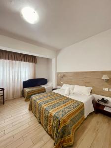 アンツィオにあるHotel La Bussolaのベッド2台とテーブルが備わるホテルルームです。