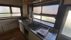a kitchen with a sink and two windows at BRIDGE Share House in Shimonoseki