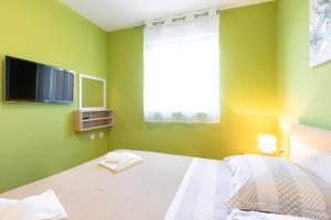 Cette chambre verte comprend un lit et une télévision murale. dans l'établissement Apartment Salvagno, à Punat