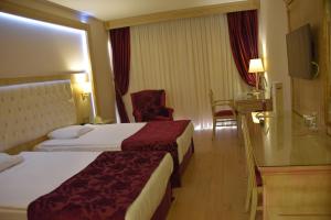 a hotel room with two beds and a chair at Ege Palas in Izmir