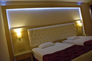 two beds in a hotel room with two lamps at Ege Palas in İzmir
