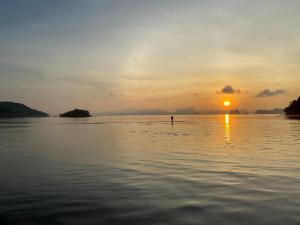 een persoon die bij zonsondergang in het water staat bij Koh Yao Seaview Bungalow in Ko Yao Noi