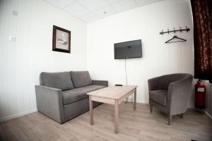a living room with two chairs and a table and a tv at Askvoll Fjordhotell in Ask