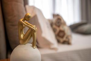 une statue d'or d'une personne assise sur un vase dans l'établissement Anastasia's Studios, à Polychrono
