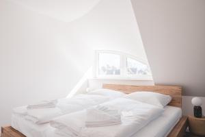 zwei weiße Betten in einem weißen Zimmer mit Fenster in der Unterkunft Reethus Reethus 2 in Born