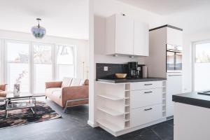 a kitchen with white cabinets and a living room at Reethus Reethus 3 in Born