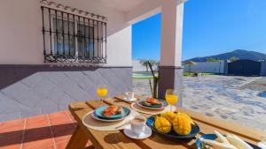 a wooden table with plates of food and orange juice at Casa Serrano Cártama by Ruralidays in Cártama