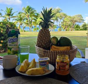 a table with a basket of fruit and a plate of food at Studio vue mer Guadeloupe in Sainte-Anne