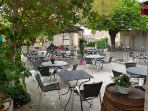 un patio al aire libre con mesas, sillas y árboles en Le Guintrand, en Bédoin