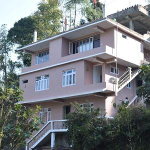 a pink building with trees in front of it at Mandavya homestay in Pelling
