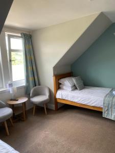 a bedroom with a bed and a chair and a window at West Loch House in West Tarbert