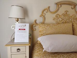 a bed with a sign on a night stand and a lamp at Casa Aurora in Ravenna