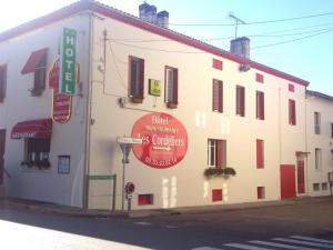 a white building with signs on the side of it at Logis Hôtels - Hôtel et Restaurant Les Cordeliers in Casteljaloux