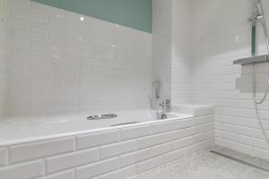 uma casa de banho branca com uma banheira e um chuveiro em Le Grand Léjon em Pléneuf-Val-André