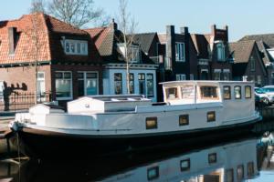 un barco sentado en el agua frente a las casas en Het Waterhotel, en Heerenveen