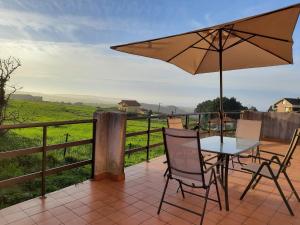 un patio con mesa, sillas y sombrilla en Con vistas al mar y aparcamiento gratis, en Suances