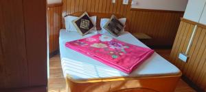 uma cama com um cobertor rosa e almofadas em Hotel Sansar Near Mall Road em Shimla