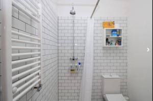 y baño de azulejos blancos con aseo y ducha. en Spacious studio flat in Forest Gate, en Londres