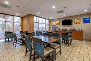 a dining room with tables and chairs and a tv at Comfort Inn & Suites Orlando North in Sanford