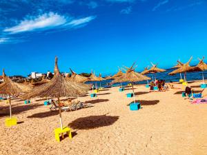 a beach with straw umbrellas and people on the sand at Arapya Resort in Arapya