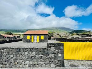 a house with yellow doors and a stone wall at Casa Flor de Sal in São Mateus