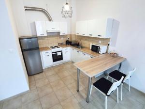 una cocina con armarios blancos y una mesa de madera con sillas. en Apartament Seven, en Legnica