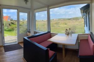 ein Wohnzimmer mit einem Sofa, einem Tisch und Fenstern in der Unterkunft Engelse Veld in Bergen aan Zee
