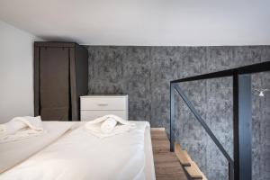 una camera con un letto bianco e una parete di cemento di BpR Lore Studio au Danube a Budapest